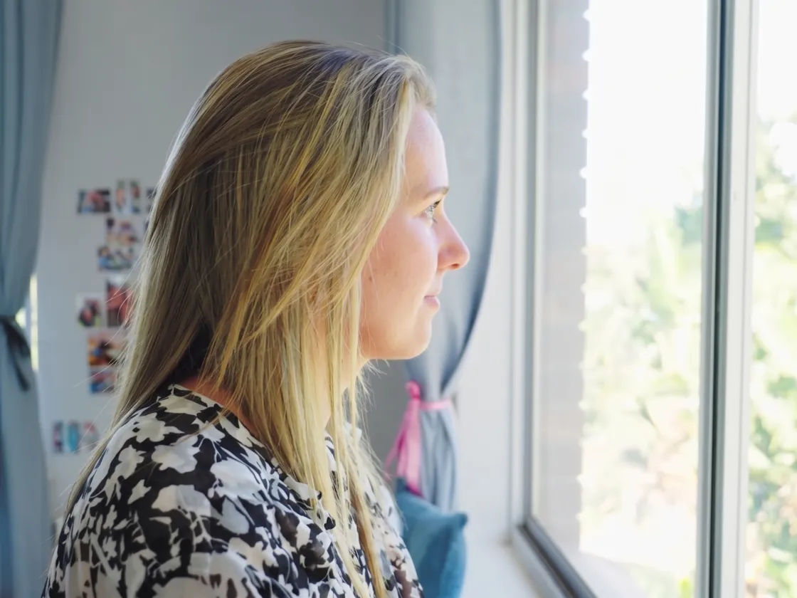 Een vrouw kijkt naar buiten vanuit een kamer bij Imani
